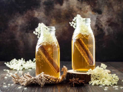 Маски с канела: две стъклени шишета с канелена вода на маса и цвят от канела