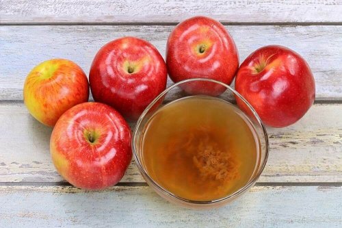 Ябълки на маса и чаша с ябълков оцет