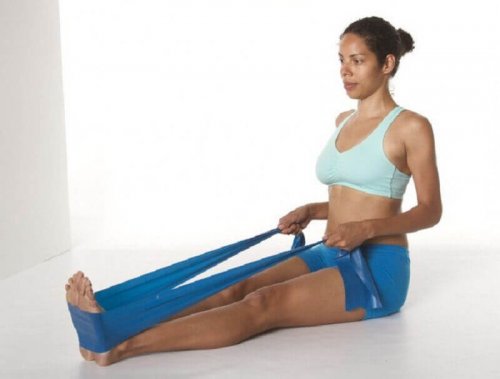 Упражнения за гърба: жена седнала на подаа с разтегателна лента