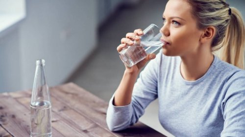 За лесно отслабване: руса млада жена е седнала на маса и пие вода