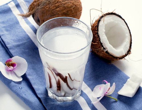 Срещу запек: кокосова вода в чаша и разрязан кокосов орех на маса