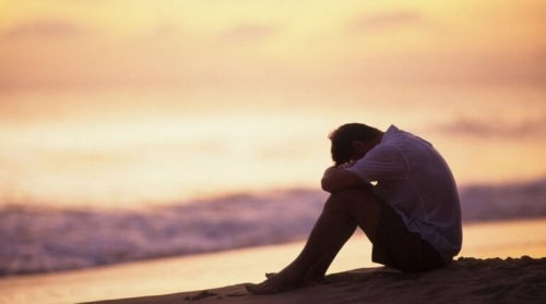 За преодоляване на депресията: мъж седнал на брега на морето при залес слънце