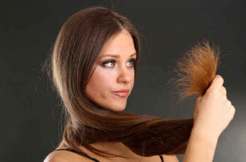 Блестяща и копринена коса: лице на жена. Жената държи краищата на увредена коса 