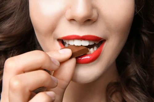 Храни, които повишават настроението: лице на млада жена, която яде шоколад 