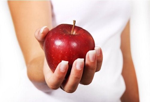Една женска ръка държи червена ябълка