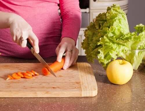 Да станете родител: една бременна жена прави салата и реже морков.