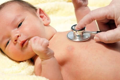 Снимка на бебе, преглеждано от лекар, със слушалка на гърдите на бебето.