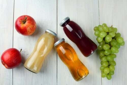 Диетични храни: снимка на 3 сока в стъклени бутилки, грозде и 2 ябълки 