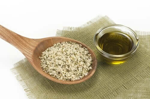 Снимка на дървена лъжица с конопени семена и на стъклена чинийка с масло от конопени семена