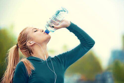 Снимка на жена, която пие вода от бутилка