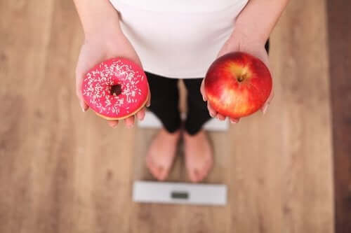 Желанието за сладко: снимка на жена, която държи в едната ръка поничка, а в другата ябълка