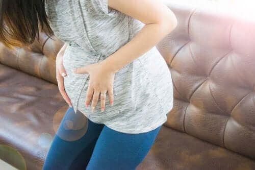 Бременна жена, която се държи за корема