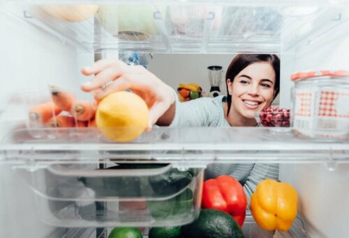 Снимка на отворен хладилник и една млада жена, която се усмихва