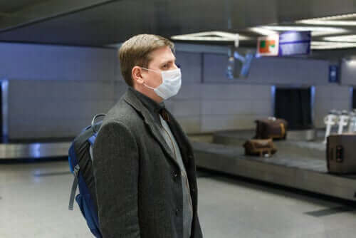 Мъж с маска, чака на летището багажа си 