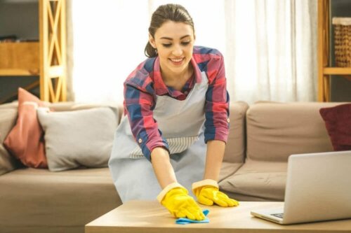 Почистване и дезинфектиране на дома: млада жена с ръкавици почиства пода