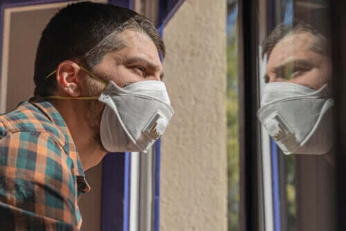 Страхът от коронавируса: мъж с маска гледа през прозореца