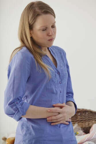 Аерофагия: жена, която има болка в стомаха и се държи за стомаха