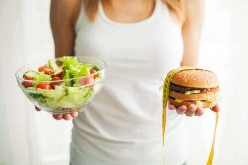 Предотвратяване на затлъстяването: една жена държи салата и хамбургер