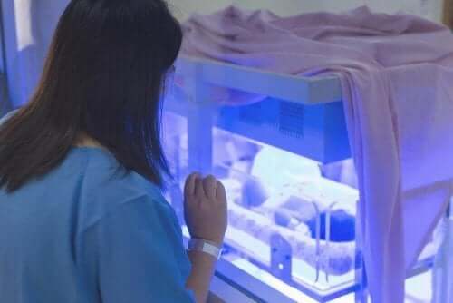 Акушерка в болница гледа бебе в кувьоз