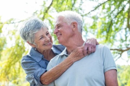 Възрастни мъж и жена прегърнати и се усмихват